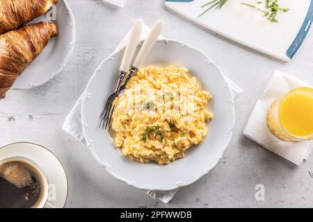Blick auf das Frühstücksmenü mit gelbem Rührei, Kaffee, Croissants und Orangensaft. Stockfoto
