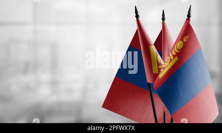 Kleine Flaggen der Mongolei auf abstraktem, verschwommenem Hintergrund. Stockfoto
