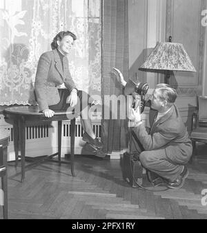 Ein professioneller Fotograf arrangiert das Fotomodell Haide Göranson so, dass er ein gutes und schmeichelhaftes Bild von ihr bekommt. Er scheint zufrieden mit der Abmachung zu sein, dass Haide auf dem Tisch sitzt. Er hält die Kamera mit dem Studio-Blitz in der Hand. Schweden 1949 Kristoffersson Ref AU1-2 Stockfoto