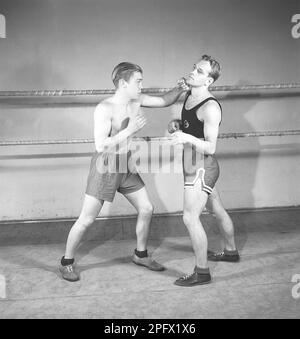 Boxen in alten Zeiten. Zwei junge Boxershorts, die sich gegenüberstehen, zum Boxen gekleidet, aber ohne Boxhandschuhe. Ein Boxer hat seine Wachsamkeit komplett verloren, und der Gegner ist schnell und landet einen linken Haken an der Wange. Schweden 1944 Kristoffersson Ref K116-3 Stockfoto