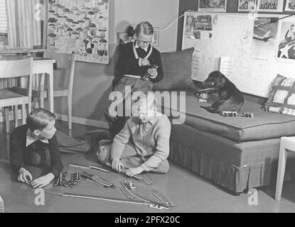 Jungs in den 1950er. Drei Jungs spielen mit einer Märklin-Modelleisenbahn. Die Teile und Schienen sind auf dem Boden angeordnet und werden elektrisch angetrieben. Ein typisches und beliebtes Spielzeug. Schweden 1953 Stockfoto