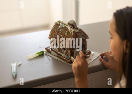 Ein Mädchen spielt mit einem Lebkuchenhaus für traditionelle Weihnachtsdekoration Stockfoto