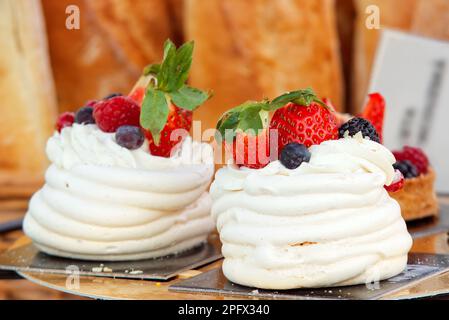 Pavlova-Desserts mit Sommerbeeren, Himbeeren, Erdbeeren, Heidelbeeren und Johannisbeeren. Nahaufnahme des Desserts am Stand von Pra Stockfoto