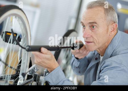 Ein älterer Mann, der ein Rad pumpt Stockfoto