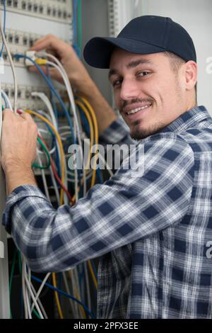 Männlicher Techniker, der die Kabel mit dem Server verbindet Stockfoto