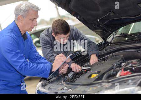 Schüler mit Lehrer, die Reparatur eines Autos während der Lehrzeit Stockfoto