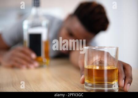 Betrunkener Mann fiel auf den Tisch und hielt Glas Stockfoto