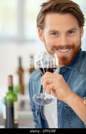 Ein fröhlicher Mann, der ein Glas Rotwein in der Hand hält Stockfoto