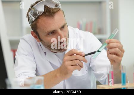 Männlicher Wissenschaftler, der Flüssigkeit im Reagenzglas analysiert Stockfoto