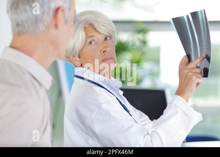 Zwei medizinische Kollegen schauen sich Röntgenbilder des Patienten an Stockfoto