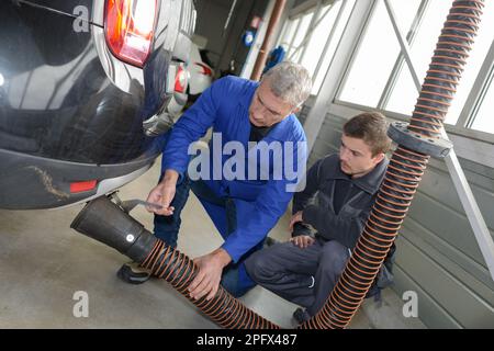 Schüler mit Lehrer, die Reparatur eines Autos während der Lehrzeit Stockfoto