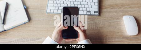 Draufsicht auf die Hände einer Geschäftsfrau, die das Telefon hält, während sie im Büro an seinem Arbeitsplatz sitzt Stockfoto