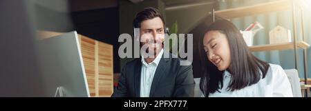 Zwei lächelnde Geschäftsleute, die in einem modernen Büro arbeiten und über ein neues Projekt diskutieren Stockfoto