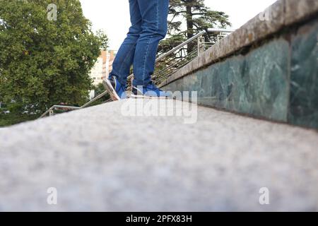 Eine Person mit blauen Jeans und Schuhen, die die Treppe hinaufgeht Stockfoto