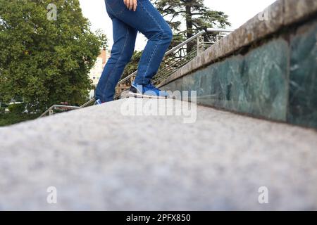 Eine Person mit blauen Jeans und Schuhen, die die Treppe hinaufgeht Stockfoto