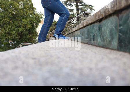 Eine Person mit blauen Jeans und Schuhen, die die Treppe hinaufgeht Stockfoto