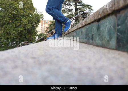 Eine Person mit blauen Jeans und Schuhen, die die Treppe hinuntergeht Stockfoto