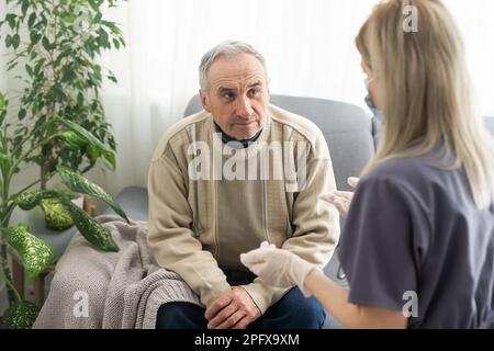 Fürsorgliche Krankenschwester spricht mit altem Patienten hält seine Hand sitzen im Wohnzimmer bei Homecare Besuch bieten psychologische Unterstützung zuhören klagt Empathie zeigen Stockfoto
