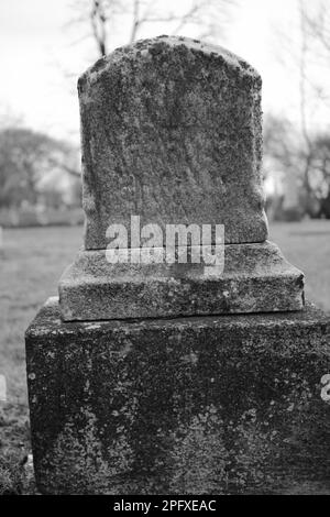 Abgenutzter und verwitterter alter Grabstein mit einer leeren Epitaphe und Platz für Text. Stockfoto