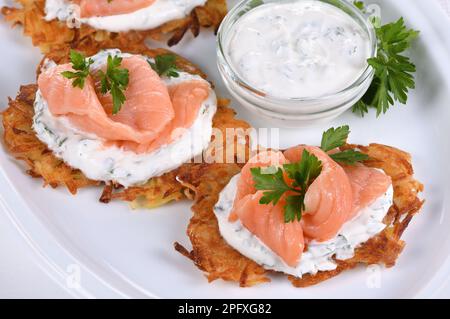 Knusprige Kartoffelbrüter (ein Pfannkuchen, besonders einer mit geriebener Kartoffel) mit Frischkäse-Sauce mit Kräutern und Lachs Stockfoto