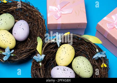 Geschenke zu Ostern, Osterverkauf. Eier in Nestern und Geschenkschachteln auf blauem Hintergrund. Stockfoto