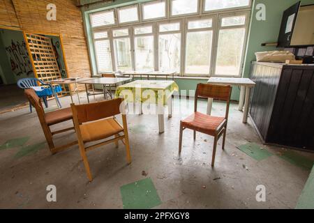 Alte, heruntergekommene Tische und Couchtische in einem verlassenen Gebäude. Stockfoto