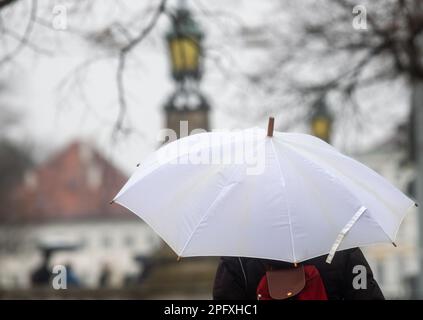 München, Deutschland. 19. März 2023. Eine Frau mit Schirm geht den Kanal des Nymphenburg-Palastes entlang. Das Wetter war nass und düster am Wochenende. Kredit: Stefan Puchner/dpa/Alamy Live News Stockfoto