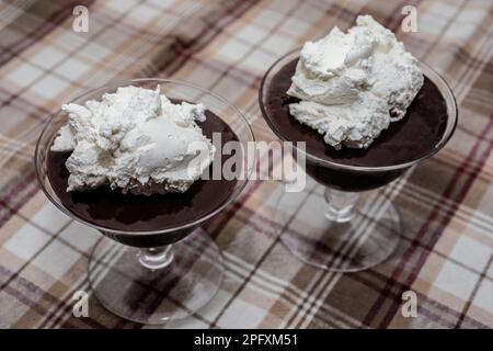 Schokoladenpudding und Schlagsahne in Dessertbechern auf einer braunen karierten Tischdecke; Taylors Falls, Minnesota, USA. Stockfoto