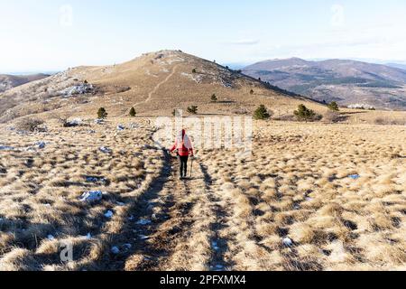 Frau, Touristin, Wandern auf einem grasbewachsenen kargen Bergmassiv auf der Halbinsel istrien, an der Grenze zwischen slowenien und kroatien am kalten Wintertag, slowenien Stockfoto