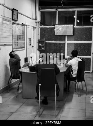 Drei Sicherheitsleute auf dem Dalat Market in Vietnam schauen sich ein Fußballspiel im Fernsehen an, das bei der FIFA-Weltmeisterschaft 2022 stattfindet. Stockfoto