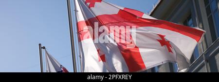 Nationalflagge Georgiens winkt im Wind auf blauem Himmel Hintergrund Stockfoto