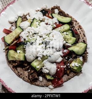 Griechische Wurst-Pizza mit Knoblauch, Tomaten, Avocado, Gurke, Fetakäse, Und Tzatziki-Sauce. Stockfoto