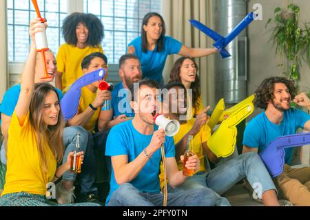 Multiethnische Gruppe von Freunden, die zu Hause ein Fußballspiel beobachten und unterstützen. Stockfoto