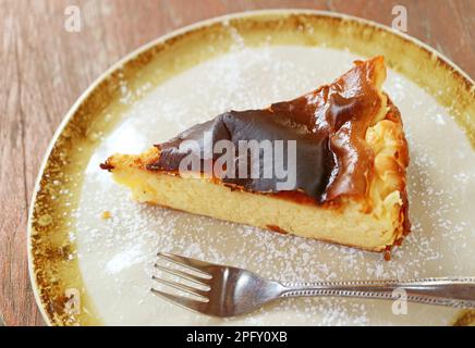 Ein Stück köstlicher baskischer Käsekuchen auf einem rustikalen Holztisch Stockfoto