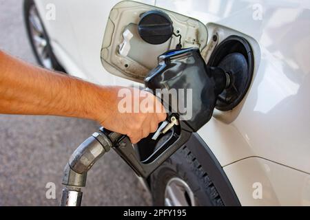 Der Fahrer, der eine Hand hält, weil er einen Tankwagen betankt, fährt ein Auto Stockfoto