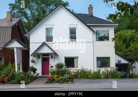Die Fassade eines kleinen Hauses ist mit Blumenbeeten und bunten Blumen dekoriert. Stockfoto