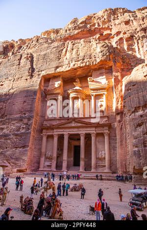 27. Januar 2023 Petra, Jordanien. Kamele und Menschen in der Nähe der archäologischen Stätten Petra Al Khazzona (der Schatzkammer) in Jordanien. Stockfoto