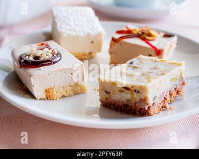 Weißer Teller mit verschiedenen Gebäckstücken. Leckere Desserts mit Belag, Kokosnussflocken. Stockfoto