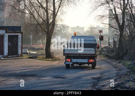 Bau- und Wartungsservice für Eisenbahnstrecken Pick-up-PKW an der Kreuzung mit Bahngleisen auf einer von Bäumen umgebenen Vorstadtstraße Stockfoto