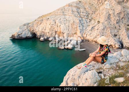 Touristenfrauen sitzen und genießen das Panorama am Aussichtspunkt auf der Insel Mirellas am persischen Golf. Musandam. Oman Stockfoto