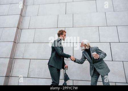 Ein Treffen. Ein junger Mann mit einem älteren Mann in eleganten Kleidern ist draußen zusammen. Geschäftskonzeption Stockfoto