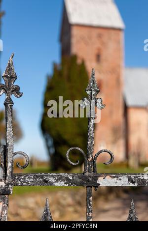 Ein vertikaler Schuss eines rostigen Zauns auf einem Friedhof unter der Sonne mit einem verschwommenen Hintergrund Stockfoto