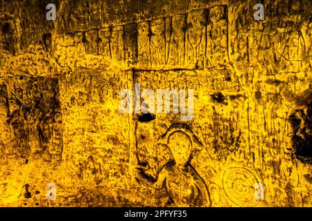 Die Royston Cave in Herfordshire, Großbritannien, verwirrt heute noch Historiker. Die Höhle ist mit einer großen Anzahl von Wandskulpturen mit niedrigem Relief dekoriert. Es sind hauptsächlich christliche Motive im mittelalterlichen Stil. Die Figur mit dem gezogenen Würm könnte den Heiligen Michael oder vielleicht den Heiligen Georg repräsentieren, der später Schutzpatron von England war. Der Würfel der Figur zeigt auf das, was Jasus und die zwölf Jünger mit Judas zu sein scheinen, die kleine Figur hinten am rechten Ende der Reihe. Royston Cave in Katherine's Yard, Melbourn Street, Royston, England Stockfoto