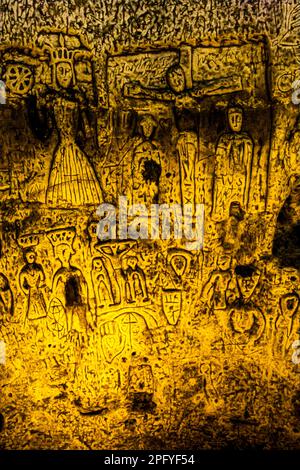 Die Royston Cave in Herfordshire, Großbritannien, verwirrt heute noch Historiker. Die Höhle ist mit einer großen Anzahl von Wandskulpturen mit niedrigem Relief dekoriert. Es sind hauptsächlich christliche Motive im mittelalterlichen Stil. St. Catherine with the Breaking Wheel ist eine der größeren christlichen Schnitzereien in der Royston Cave in Katherine's Yard, Melbourn Street, Royston, England Stockfoto