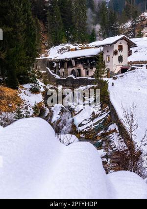 Sappada, Italien - 30. Dezember 2022: Idyllisches Winterfoto einer verlassenen Wassermühle in Sappada, einem alpinen Dorf am Rande der italienischen Dolomiten Stockfoto