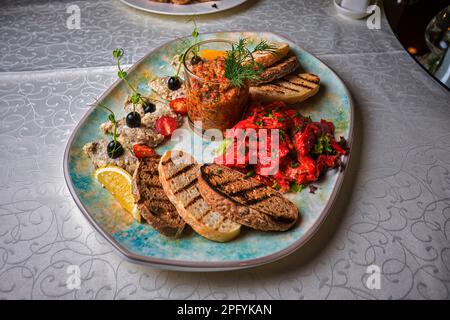 Bankett-Gemüse-Snacks und Toast auf einem Teller, auf dem Tisch, verschwommener Hintergrund Stockfoto
