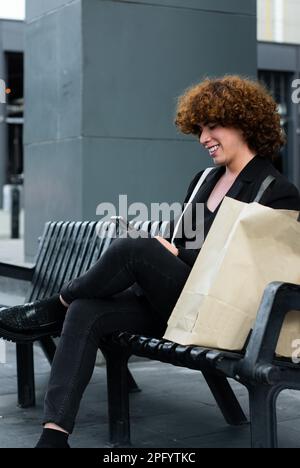 Eine Person, die nicht binär ist, scrollt auf dem Smartphone und sieht sich soziale Medien an Stockfoto