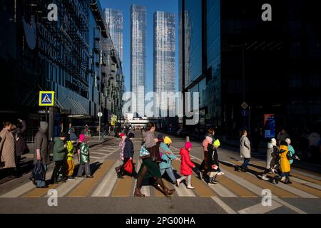 Moskau, Russland. 19. März 2023. Die Menschen überqueren eine Straße an einer Fußgängerüberquerung im Finanzviertel von Moskau und dem Wolkenkratzer-Viertel von Moskau, Russland Stockfoto