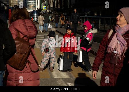 Moskau, Russland. 19. März 2023. Die Menschen überqueren eine Straße an einer Fußgängerüberquerung im Finanzviertel von Moskau und dem Wolkenkratzer-Viertel von Moskau, Russland Stockfoto