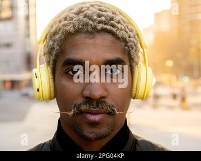 Nahaufnahme eines ernsthaften afroamerikanischen Mannes mit Schnurrbart und Kopfhörern, der in die Kamera schaut Stockfoto